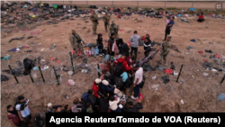 Migrantes intentan cruzar una valla de alambre de púas desplegada para impedir el cruce de migrantes a EEUU, a orillas del río Bravo, en la frontera con México.