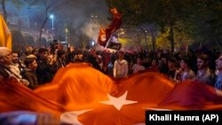 Partidarios del presidente de Turquía, Recep Tayyip Erdogan, celebran ante la sede del Partido Justicia y Desarrollo en Estambul, Turquía, el domingo 14 de mayo. (AP Foto/Khalil Hamra)