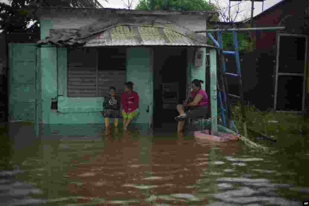 Residentes contemplan el frente de su vivienda lleno de agua, en Batabanó. 