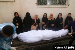 Mujeres palestinas esperan junto al cadáver de una persona muerta en un bombardeo israelí sobre la Franja de Gaza, en Rafah, el 24 de octubre de 2023. (AP Foto/Hatem Ali)