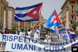 Miembros de la comunidad cubana en Italia ondean banderas del país y cantan consignas contra el presidente de Cuba, Miguel Díaz-Canel durante su visita al Vaticano. (AP/Domenico Stinellis)