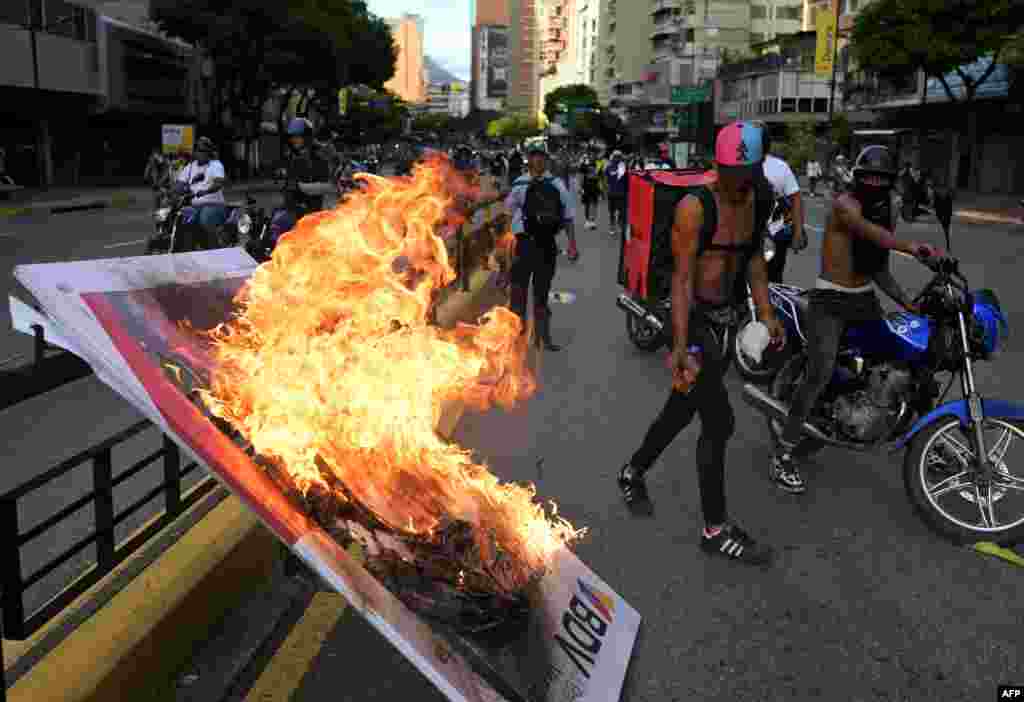 Manifestantes queman una pancarta publicitaria durante protesta contra Nicolás Maduro en Caracas el 29/07/2024 (Foto de YURI CORTEZ / AFP)