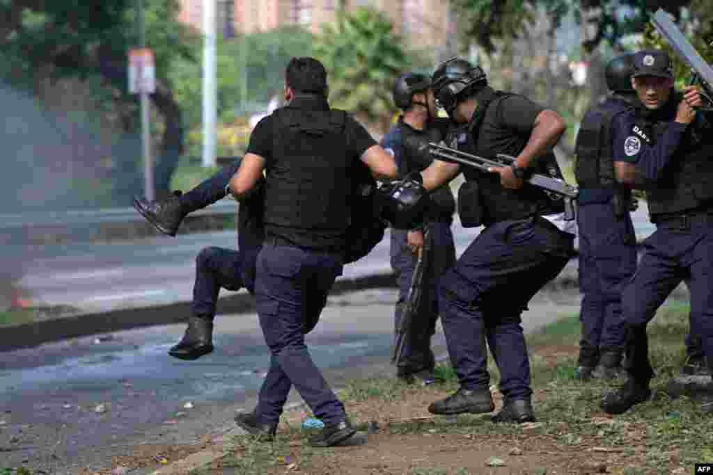 Oficial de policía lleva a un colega herido durante protesta contra el presidente Nicolás Maduro en Caracas el 29 de julio de 2024, (Foto de Yuri CORTEZ / AFP)