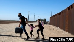 Una familia de migrantes cubanos se apresura a cruzar la frontera en Yuma, Arizona, en mayo de 2021. (Ringo Chiu/ AFP).