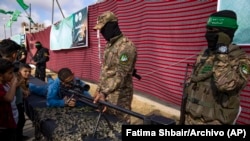 Un niño palestino posa con un arma en una exhibición de armas para el ala militar del grupo gobernante Hamas en el campo de refugiados de Nusseirat, en el centro de la Franja de Gaza. (AP/Fatima Shbair/Archivo)