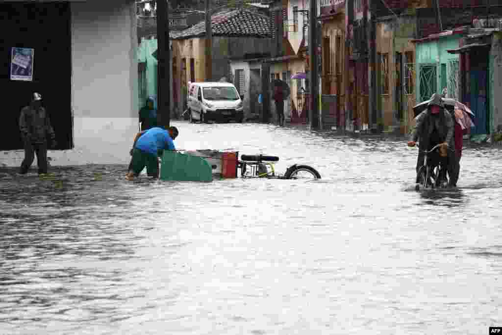 En esta fotografía difundida por ACN, se ve a personas en una calle después de que las fuertes lluvias provocaron una inundación en Camagüey, Cuba, el 9 de junio de 2023.