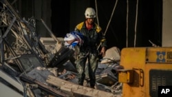 Un rescatista carga una bandera cubana recuperada en el lugar de una explosión mortal que dañó el hotel Saratoga, en La Habana, el viernes 6 de mayo de 2022. (AP Foto/Ramón Espinosa)