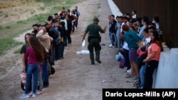 Un grupo de migrantes espera a ser procesado junto al muro fronterizo, en Eagle Pass, Texas. (AP/Dario Lopez-Mills, File)