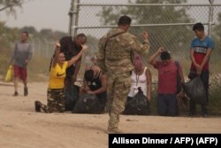 La inmigrante cubana Magdalena Ávila (arrodillada a la izquierda) y otras personas se emocionan después de cruzar ilegalmente la frontera sur de EEUU, el 9 de octubre de 2022 en Eagle Pass, Texas.