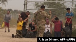 La inmigrante cubana Magdalena Ávila (arrodillada a la izquierda) y otras personas se emocionan después de cruzar ilegalmente la frontera sur de EEUU, el 9 de octubre de 2022 en Eagle Pass, Texas. (Allison Dinner/AFP).