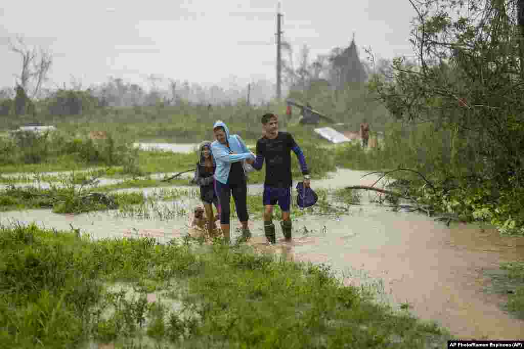 Una familia camina bajo la lluvia en busca de refugio después de que su casa se inundara cuando el huracán Ian azotó Pinar del Río, Cuba, el martes 27 de septiembre de 2022.