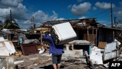 Un residente lleva a cuestas una lavadora dañada después del paso del huracán Ian en Cuba en 2022 / Foto: Yamil Lage (AP)