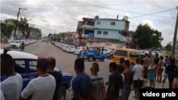 Cubanos observan dos hileras de carros patrulleros apostados cerca de la manifestación el 29 de septiembre.