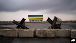 Barreras antitanque yacen frente a una casa pintada con los colores de la bandera ucraniana en las afueras de Kiev, Ucrania. (AP Foto/Rodrigo Abd)