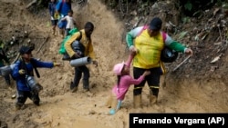 Una mujer tira de una niña para sacarla del lodo mientras atraviesan el tapón del Darién. (AP Foto/Fernando Vergara, Archivo)