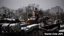 Un niño subido a un tanque ruso destruido y expuesto en el centro de Kyiv, Ucrania, el 31 de enero de 2023. (AP Foto/Daniel Cole)