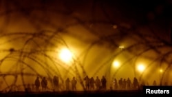 Migrantes se encuentran cerca del muro fronterizo durante una tormenta de arena después de haber cruzado la frontera entre Estados Unidos y México para entregarse a los agentes de la Patrulla Fronteriza de Estados Unidos. REUTERS/José Luis González