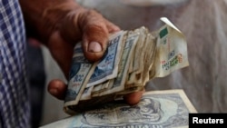 Un hombre sostiene pesos cubanos. REUTERS/Desmond Boylan