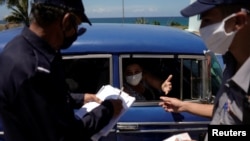 La policía revisa documentos de los pasajeros de un auto en el punto de control de Boca de Jaruco, en Mayabeque. (Alexandre Meneghini/Reuters).