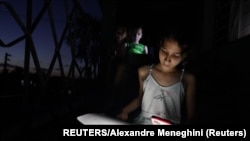 Una niña hace la tarea con la luz de su celular en medio de un apagón en La Habana, Cuba. (REUTERS/Alexandre Meneghini/Archivo)