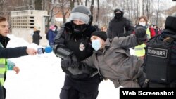 Un hombre vestido con un chaleco de prensa sostiene un micrófono mientras la policía lo detiene durante una manifestación en apoyo a Aleksei Navalny en San Petersburgo el 31 de enero de 2022.