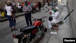 Un policía ordena a un trompetista parar de tocar en una calle de La Habana, en las cercanías de una cola para comprar alimentos. REUTERS/Alexandre Meneghini 