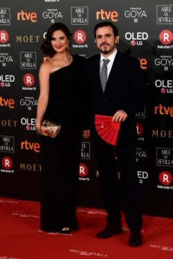 Alberto Garzón y su esposa, Anna Ruiz, posan en la alfombra roja de los Premios Goya en febrero de 2018 en Madrid. Muestra el abanico de la campaña "Más Mujeres", a favor de la presencia femenina en la industria cinematográfica y televisiva (Foto: Pierre-Philippe Marcou/AFP).