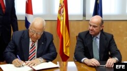 El ministro español de Economía y Competitividad en funciones, Luis de Guindos (d), y el vicepresidente del Consejo de Ministros de Cuba, Ricardo Cabrisas Ruiz (i), durante la firma de los acuerdos para reestructurar la deuda cubana con España a medio y l