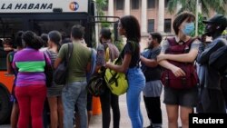 Cubanos hacen fila para subir a un transporte en La Habana.