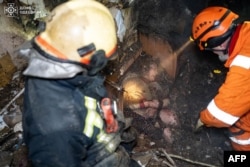 Rescatistas liberando a una mujer de los escombros en un edificio residencial dañado luego de un ataque con drones en Odesa, en el segundo aniversario de la invasión rusa de Ucrania. (Foto de Handout / SERVICIO DE EMERGENCIA DE UCRANIANO / AFP)