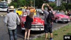 Turistas en La Habana se toman fotos sobre un "almendrón" americano de los años 50. 