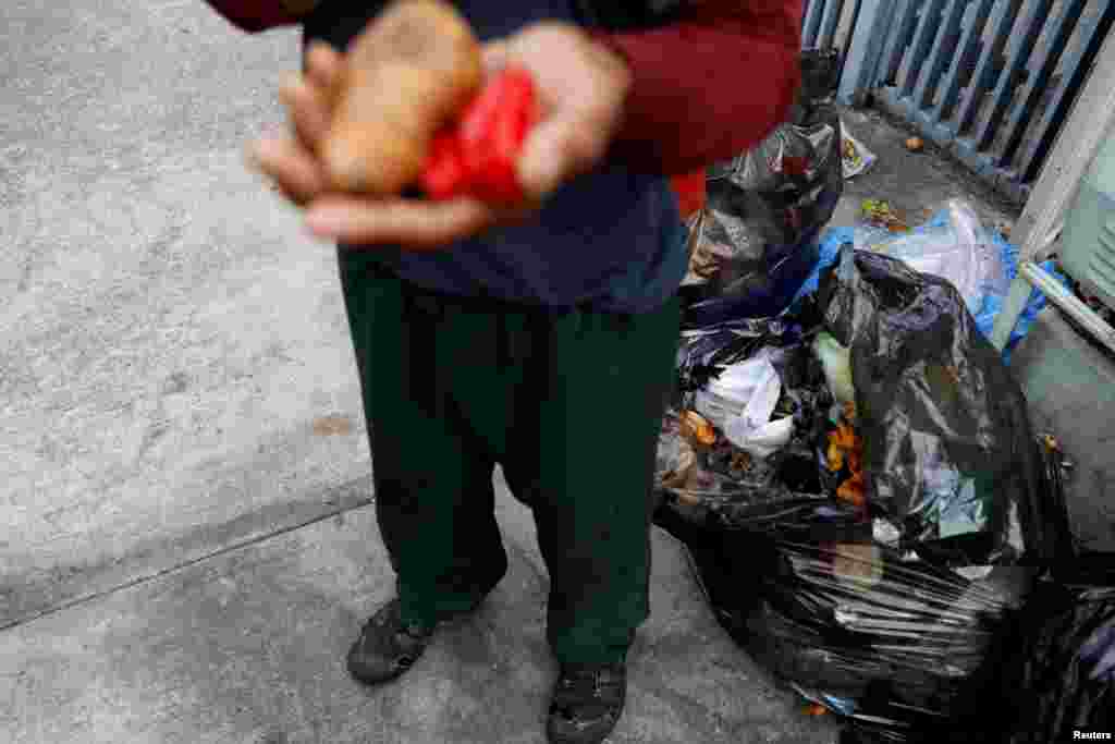 Un hombre sostiene las verduras que encontró en un contenedor de basura en Caracas, Venezuela, el 27 de febrero de 2019.