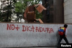 Un niño pasa junto a un graffit contra Nicolás Maduro durante un apagón en Caracas.