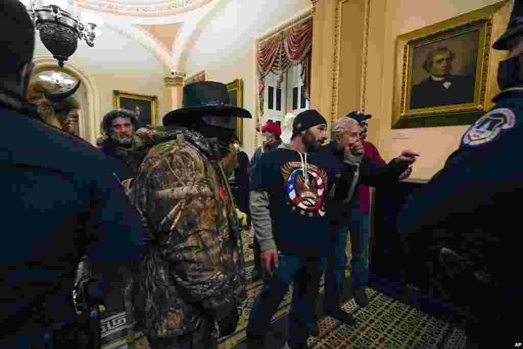 Manifestantes caminan mientras los oficiales de polic&#237;a del Capitolio de los Estados Unidos observan en un pasillo cerca de la c&#225;mara del Senado, en el Capitolio, en Washington. (AP / Manuel Balce Ceneta)