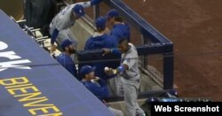 Yasiel Puig sostiene en su mano izquierda la pelota que bateó de jonrón el japonés Maeda.