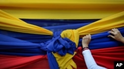 Una de las partidarias de la oposición sostiene una tela con los colores de la bandera venezolana antes de un mitin con el líder opositor Juan Guaidó en Caracas. [Archivo]