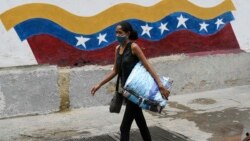 Una mujer pasa junto a un cartel que llama al uso de la máscara como protección contra el coronavirus. (AP/Matias Delacroix)