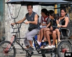 Dos mujeres viajan con sus hijas en un bicitaxi.