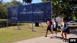 Jóvenes caminan frente a un cartel de la II Cumbre de la Celac.