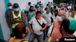 Personas esperan para comprar en un mercado mayorista en La Habana.