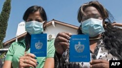 Inmigrantes cubanas muestran sus pasaportes mientras protestan frente a la agencia de la ONU para refugiados en Costa Rica. Ezequiel BECERRA / AFP