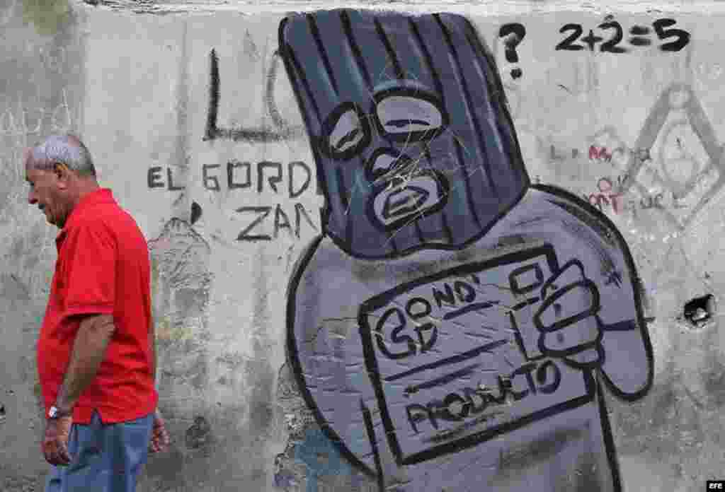 Un hombre camina junto a un grafiti alusivo a la libreta de abastecimiento en una calle de La Habana (Cuba), este viernes, 20 de enero de 2017, día en que Donald Trump asume la presidencia de EEUU. Washington y La Habana han desarrollado una frenética actividad bilateral en las últimas semanas, pues con la salida de Barack Obama de la Casa Blanca y la llegada de Trump la continuidad del deshielo iniciado en el 2014 se tiñe de incertidumbre, dado que el nuevo mandatario ha insistido en que no está de acuerdo con este proceso. &nbsp;