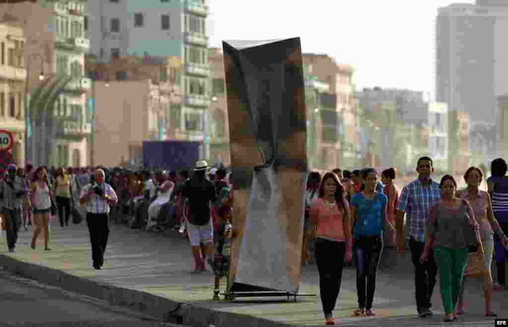 Personas caminan junto a la obra "Implosión" de Ewerdt Hilgemann expuesta en el Malecón hoy, domingo 24 de mayo, donde ha sido inaugurada la exposición "Detrás del Muro" como parte de la XII Bienal de Arte de La Habana.