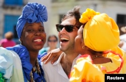 Modelos vestidas al estilo colonial besan a un turista en La Habana.