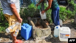 Un cubano llena contenedores de agua. (Archivo)