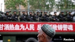 Un hombre uigur observa un camión que transporta policías paramilitares durante un mitin de juramento antiterrorista en Urumqi, Región Autónoma Uigur de Xinjiang, en 2014.