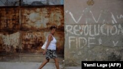 A woman walks along a street in Havana on April 18, 2018 as the National Assembly holds a session that will select Cuba's Council of State ahead of the naming of a new president. - Cuban President Raul Castro steps down Thursday, passing the baton to a ne