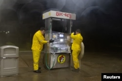 Trabajadores envuelven plástico alrededor de una bomba de combustible para protegerla del viento y la lluvia en Buc-ee's, en Freeport, Texas, el 8 de julio de 2024. REUTERS/Adrees Latif