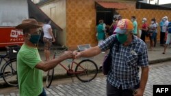 El saludo de dos cubanos en una calle de La Habana en vísperas del Día de los Pades (Yamil Lage/AFP).