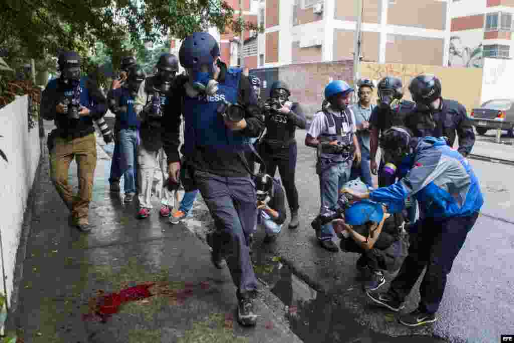 Periodistas registran una mancha de sangre de un miembro de la Policía Nacional Bolivariana (GNB) herido mientras las autoridades intentaban dispersar un grupo de manifestantes opositores al Gobierno.